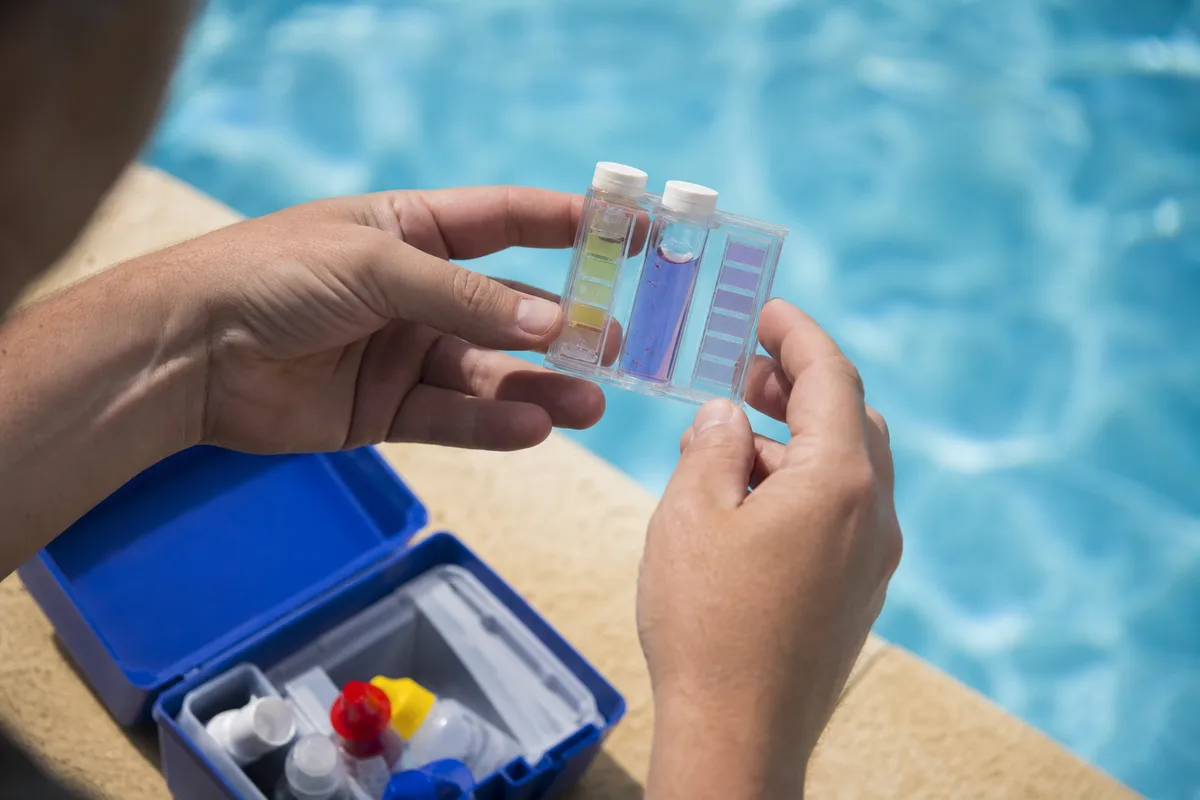 Contrôle du pH d&rsquo;une eau de piscine avec une trousse d&rsquo;analyse au bord du bassin