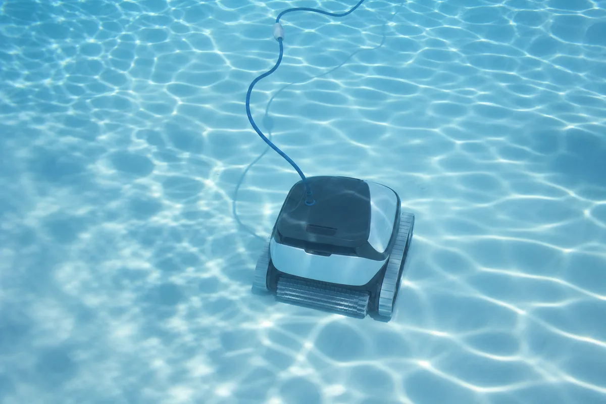 Robot nettoyeur électrique en action au fond d’un bassin bleu clair