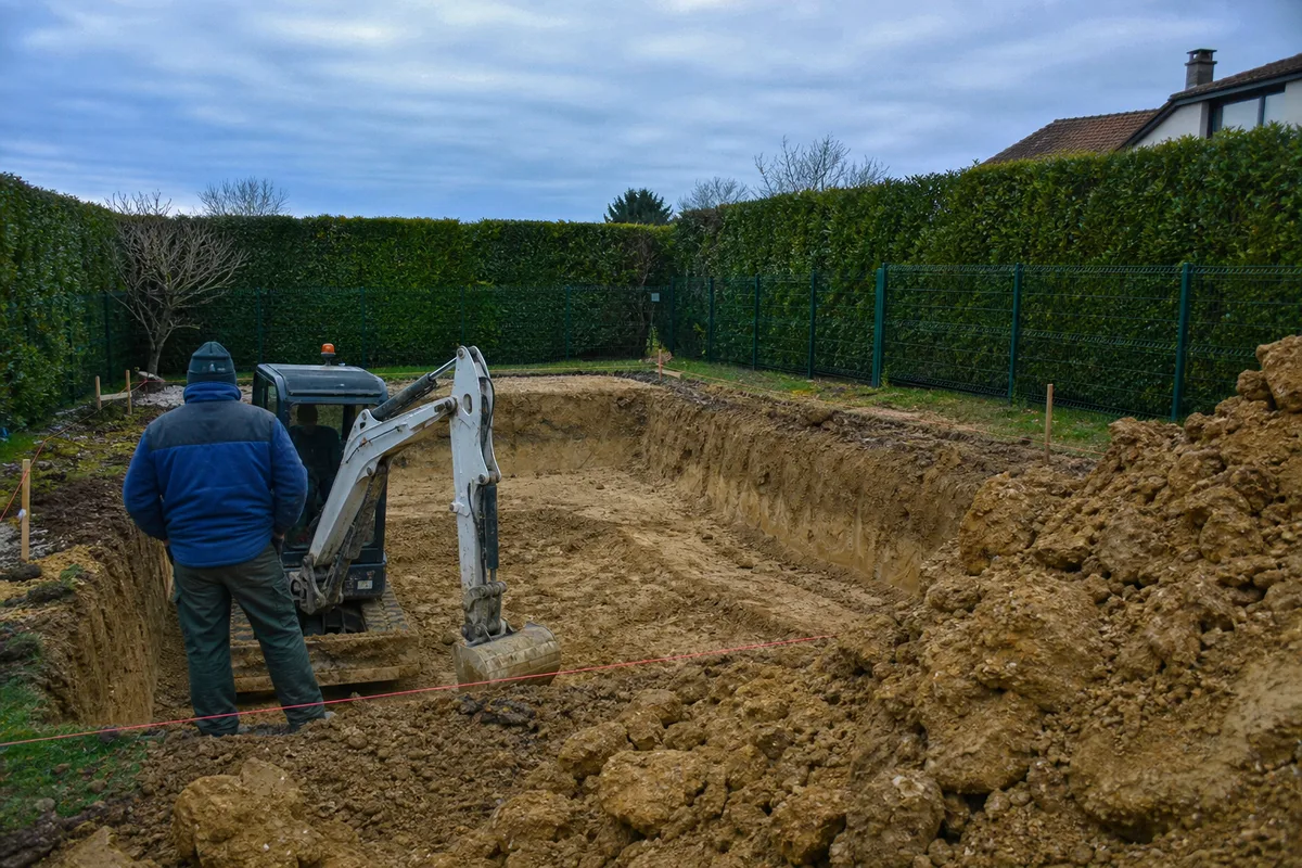 Terrassement d&rsquo;une piscine dans un jardin de l&rsquo;agglomération troyenne avec engin et terre argileuse